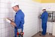 Foto FotoMural Workteam installing electrics in a tiled room foto 134114